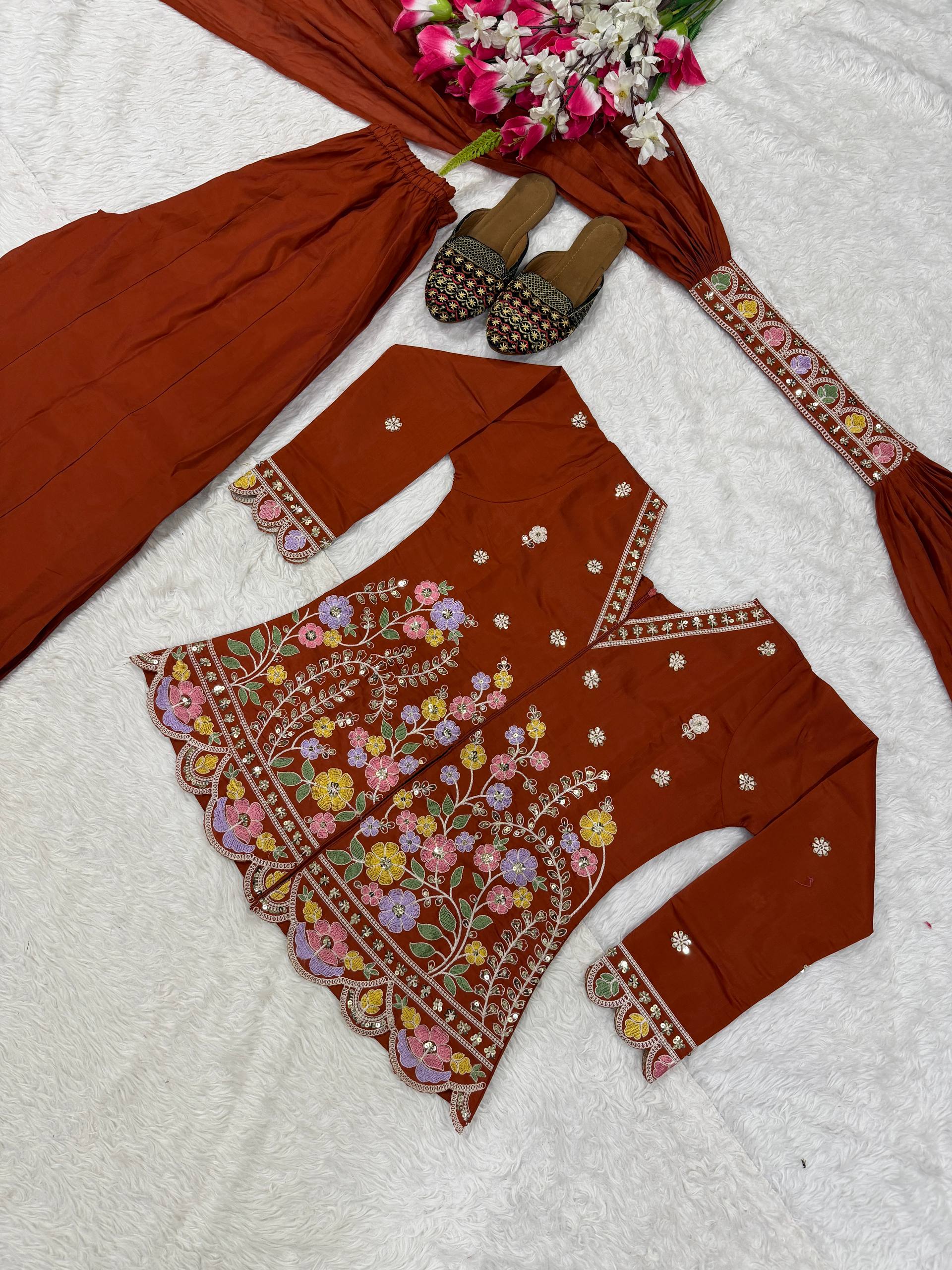 Resplendent Rust Orange Peplum Kurti and Flared Palazzo Suit Set Adorned with Intricate Multicolored Floral Embroidery, Sequin Accents, and Ornate Scalloped Borders